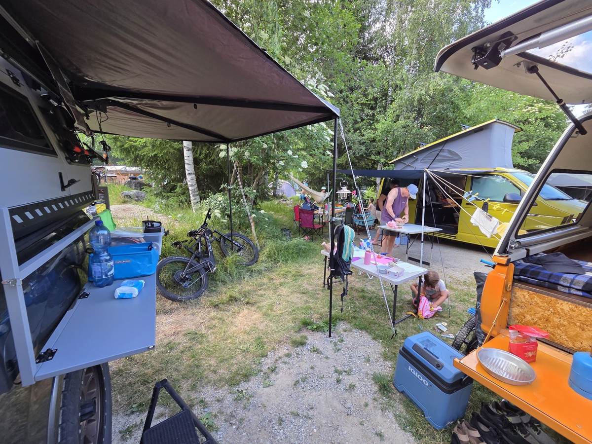 Ausgefahrene Markise mit Sitzgruppe auf einem Campingplatz, Familie beim gemeinsamen Campalltag